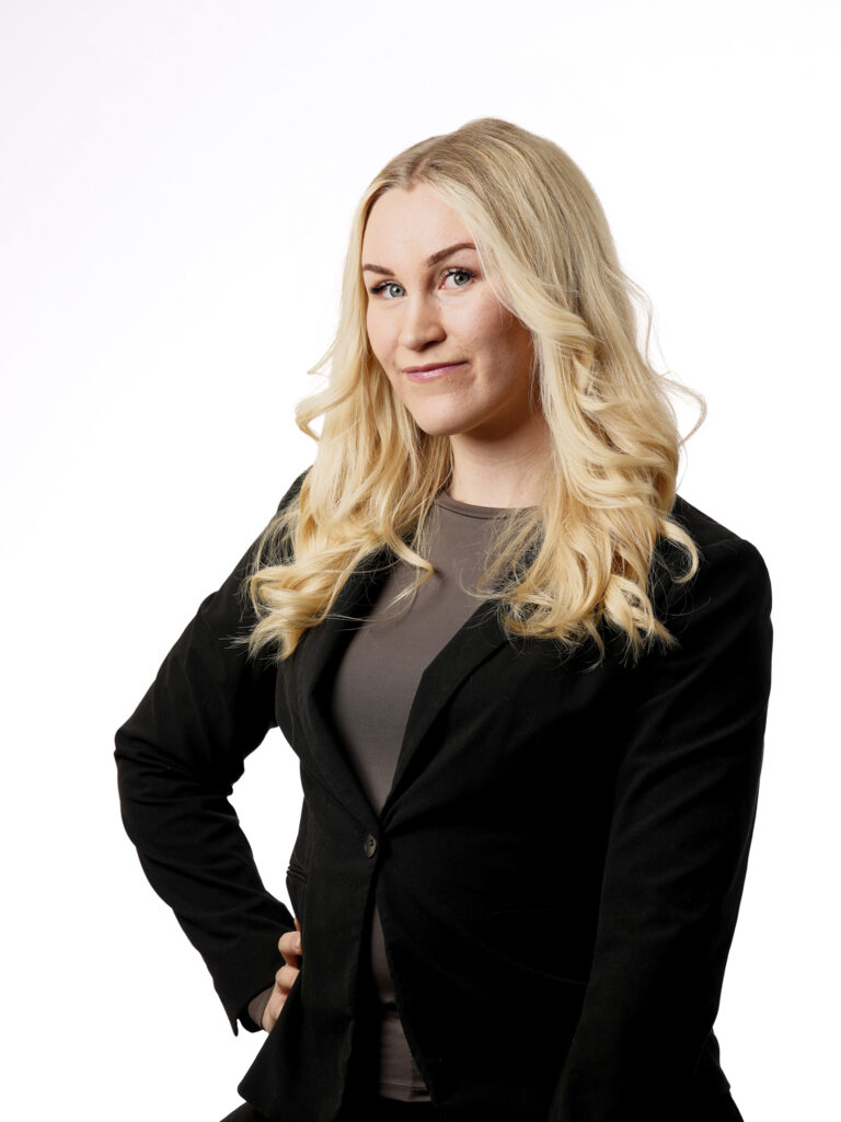 Kuva parturi-kampaaja Lotasta poseeraamassa mustassa paidassa