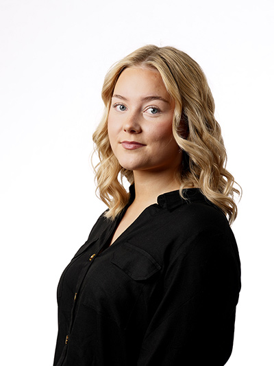 Kuva parturi-kampaaja Linasta poseeraamassa mustassa paidassa