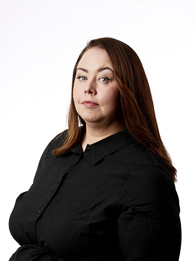 Kuva parturi-kampaaja Sussista poseeraamassa mustassa paidassa